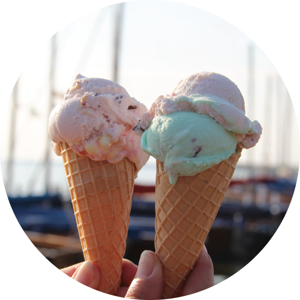 two ice cream cones being held in font of a marina